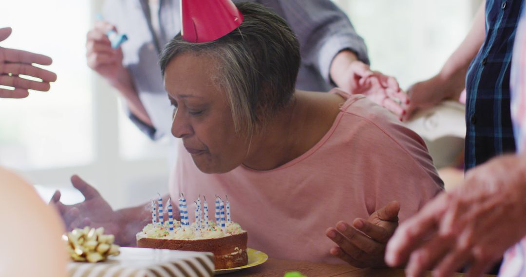 Senior Woman Blowing Candles Surrounded by Friends - Free Images, Stock Photos and Pictures on Pikwizard.com