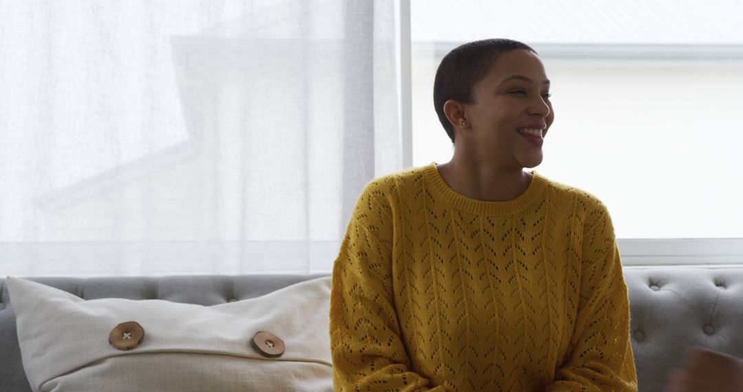 Smiling Woman In Yellow Sweater Sitting on Modern Sofa - Free Images, Stock Photos and Pictures on Pikwizard.com