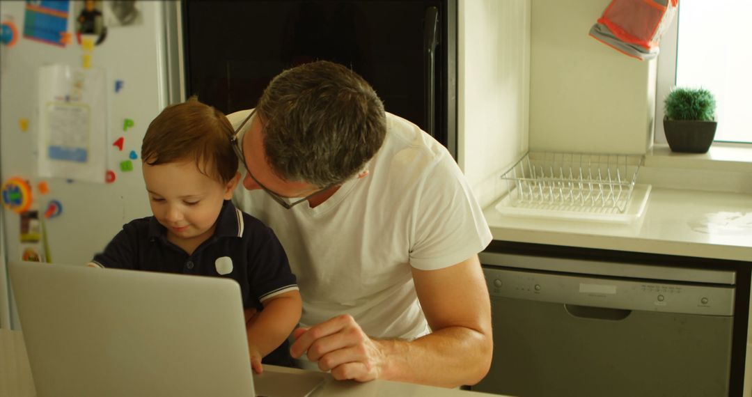 Father and Child Using Laptop in Kitchen - Free Images, Stock Photos and Pictures on Pikwizard.com