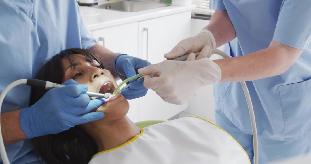 Dental team performing oral exam using suction and mirror on reclining patient