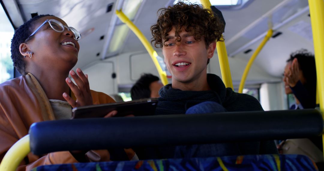 Two Young Friends Laughing and Using Tablet on Public Bus - Free Images, Stock Photos and Pictures on Pikwizard.com