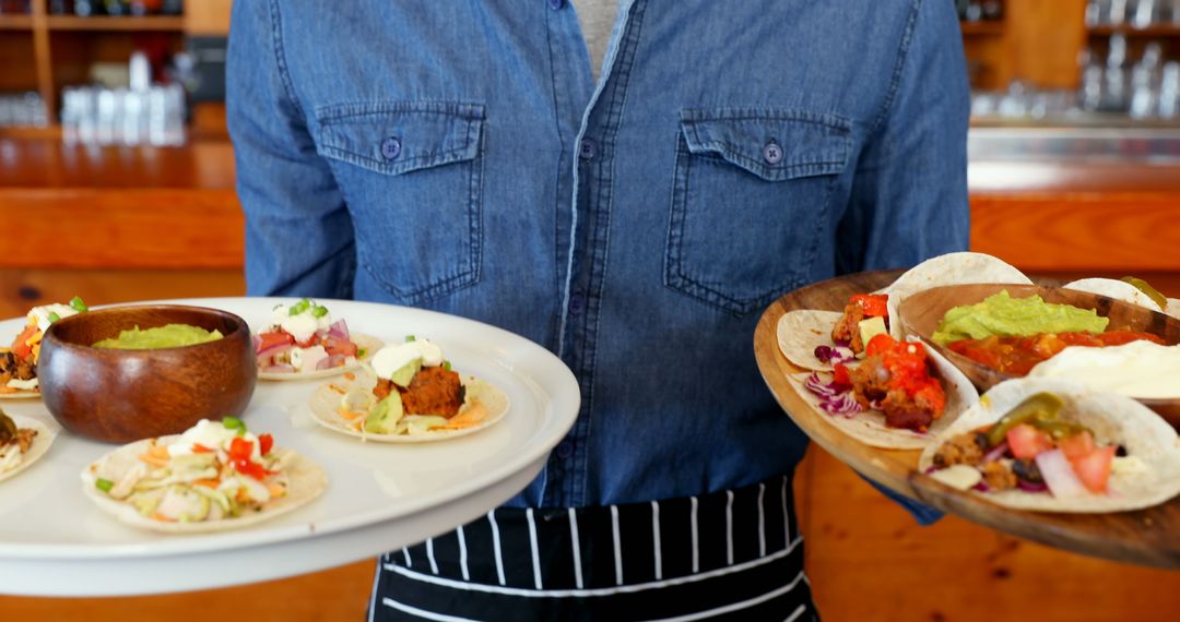 Waiter in Denim Shirt Serving Delicious Tacos on Wooden Trays - Free Images, Stock Photos and Pictures on Pikwizard.com