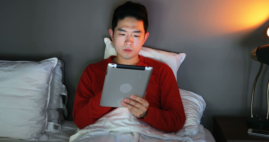 Young Man Using Tablet in Bed at Night under Warm Light - Free Images, Stock Photos and Pictures on Pikwizard.com