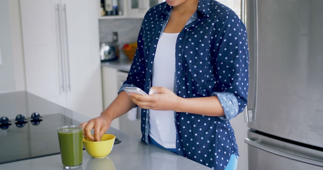 Woman Using Smartphone While Preparing Healthy Drink in Modern Kitchen - Free Images, Stock Photos and Pictures on Pikwizard.com