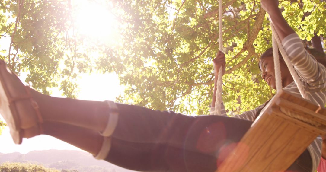 Young Woman Enjoying Swing in Sunlit Park