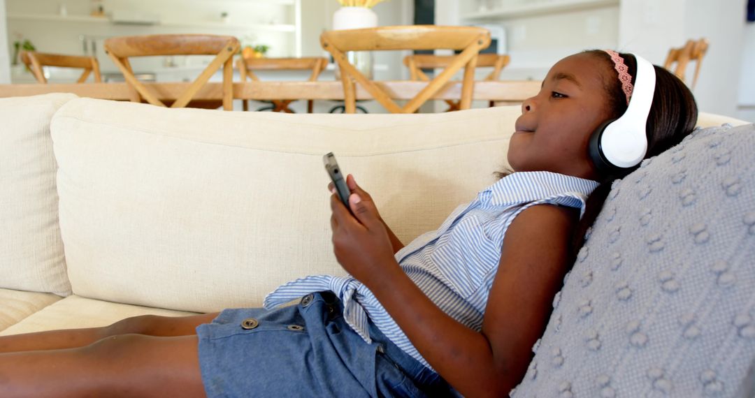 Child Relaxing on Sofa with Headphones and Smartphone