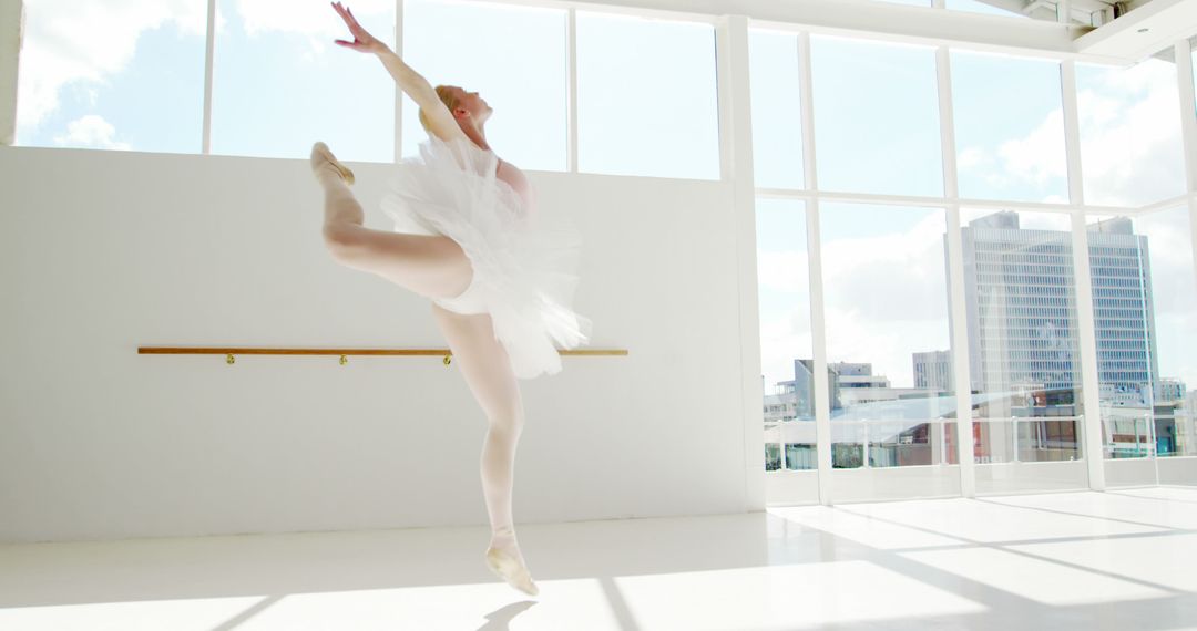 Elegant Ballet Dancer Performing Graceful Jump in Sunlit Studio