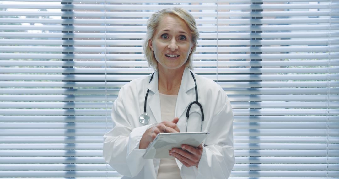 Senior Female Doctor Smiling and Taking Notes on Clipboard - Free Images, Stock Photos and Pictures on Pikwizard.com