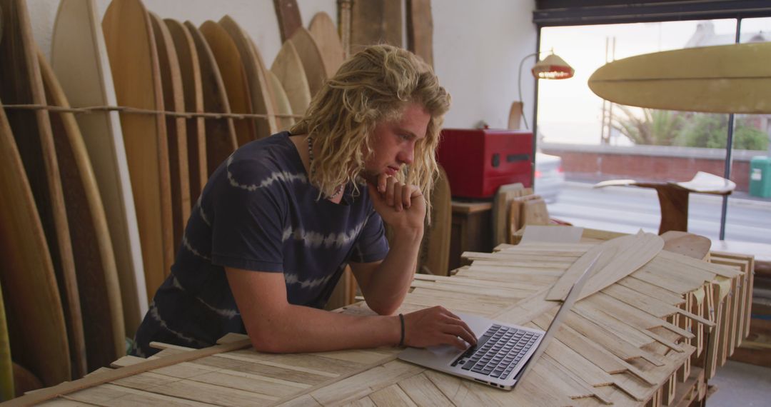 Young Man Using Laptop in Surfboard Shop - Free Images, Stock Photos and Pictures on Pikwizard.com