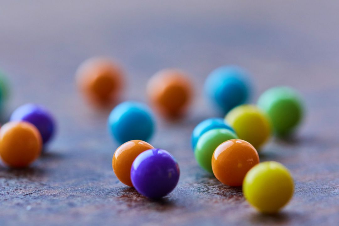 Bright Candy Spheres Scattering on Rustic Surface Macro Close-Up with Shallow Depth of Field