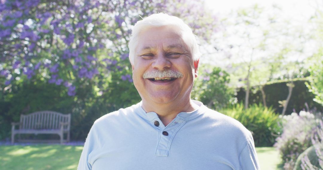 Senior man smiling in sunny garden - Free Images, Stock Photos and Pictures on Pikwizard.com