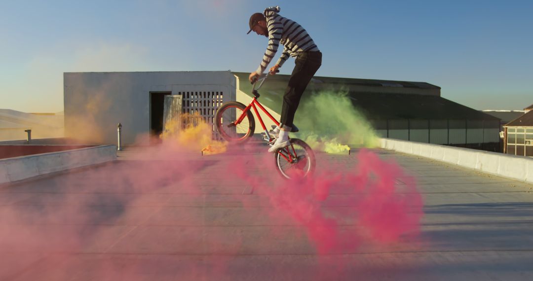 BMX Rider Performing Stunts with Colorful Smoke Bombs on Rooftop - Free Images, Stock Photos and Pictures on Pikwizard.com