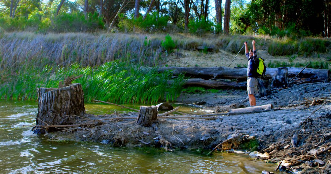 Backpacker Triumphantly Standing on Riverbank in Nature Reserve - Free Images, Stock Photos and Pictures on Pikwizard.com