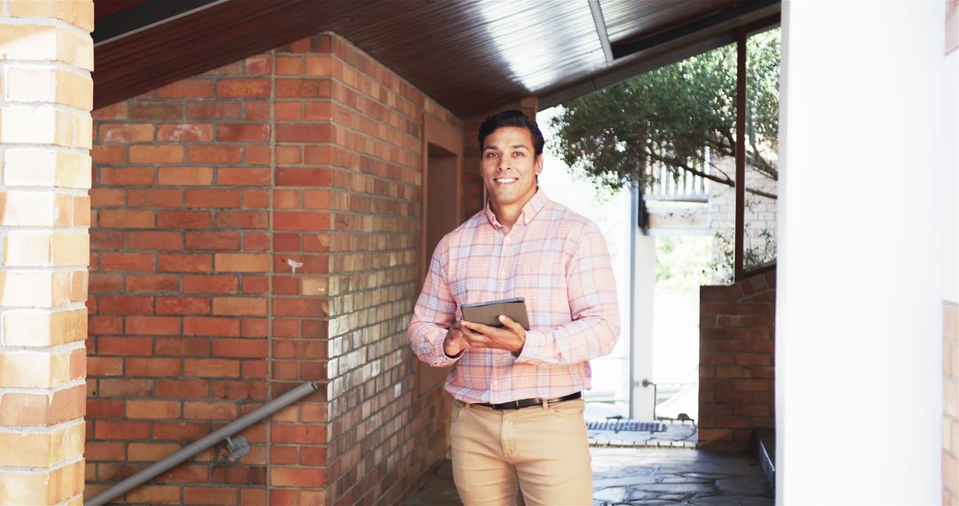 Smiling Businessman Holding Tablet in Modern Office Hallway - Free Images, Stock Photos and Pictures on Pikwizard.com