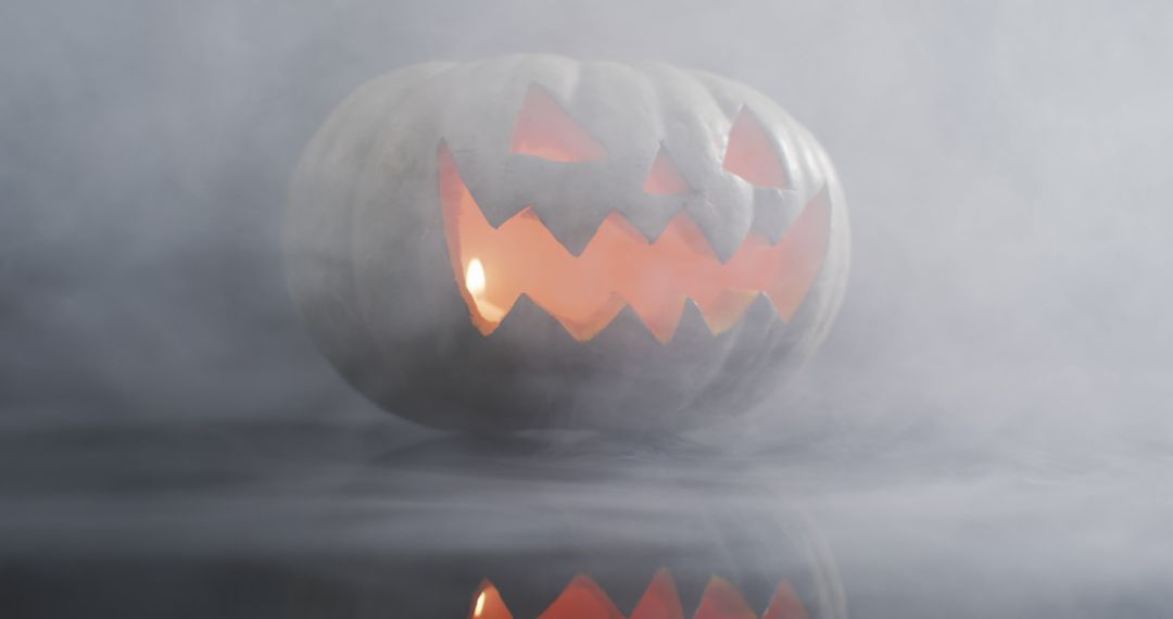 Smoke effect over scary face carved halloween pumpkin against grey background - Free Images, Stock Photos and Pictures on Pikwizard.com
