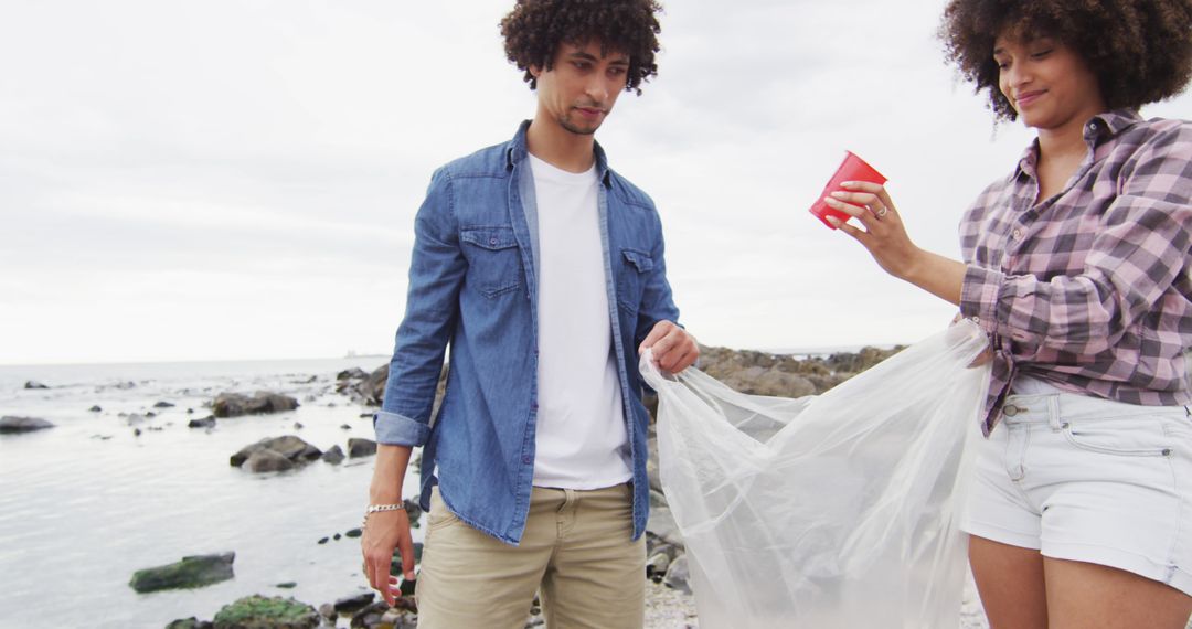 Two Young Adults Collecting Litter on Beach - Free Images, Stock Photos and Pictures on Pikwizard.com