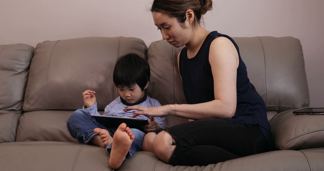 Mother and Child Sitting on Couch Using Tablet Together - Free Images, Stock Photos and Pictures on Pikwizard.com