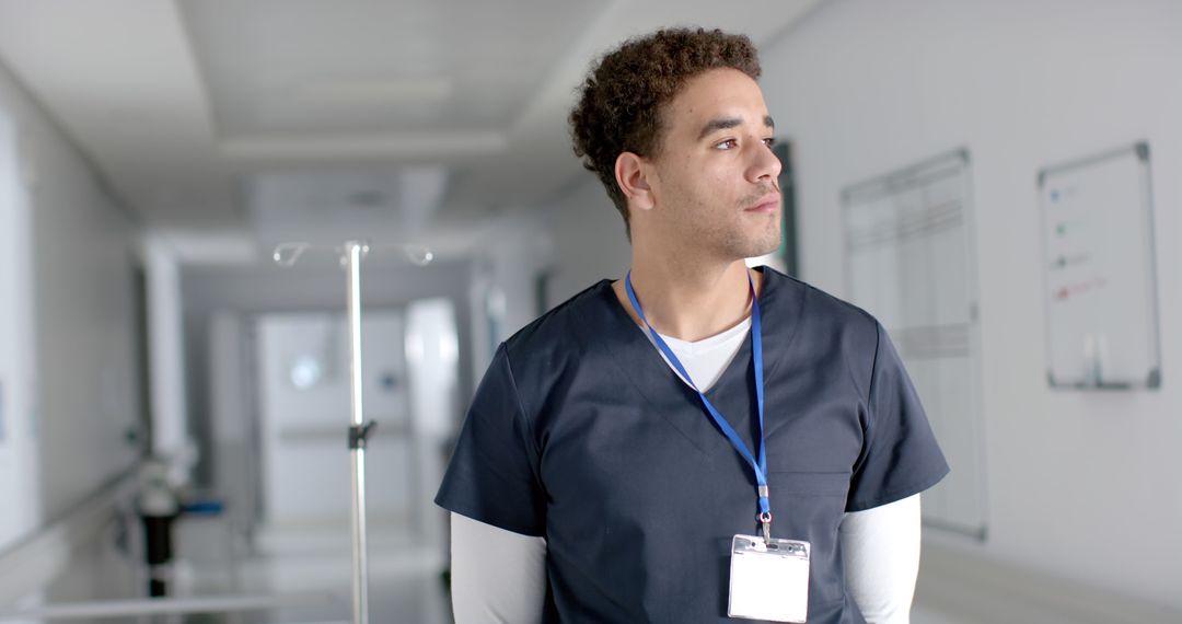 Young Healthcare Professional in Hospital Corridor Looking Thoughtful - Free Images, Stock Photos and Pictures on Pikwizard.com