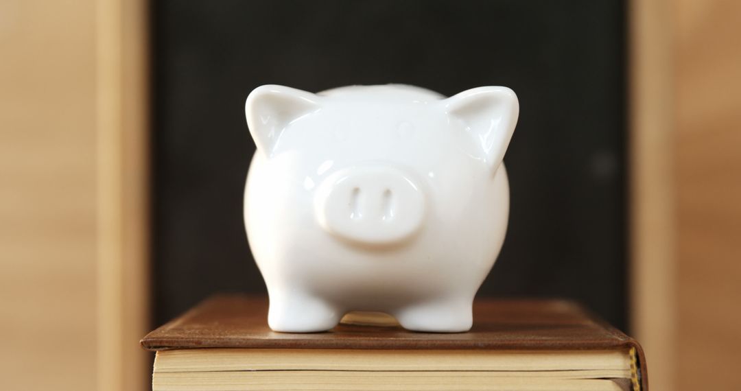 White ceramic piggy bank on stack of books in classroom - Free Images, Stock Photos and Pictures on Pikwizard.com