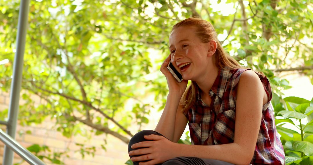 Teenage Girl Laughing While Talking on the Phone Outdoors - Free Images, Stock Photos and Pictures on Pikwizard.com