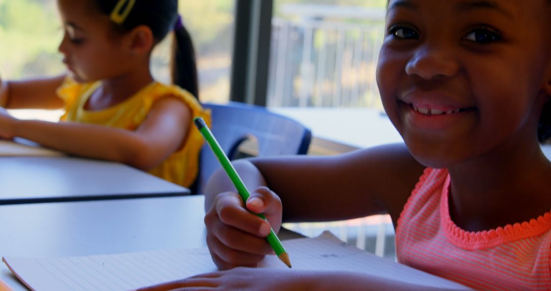 Smiling Schoolgirl Writing at Desk in Classroom