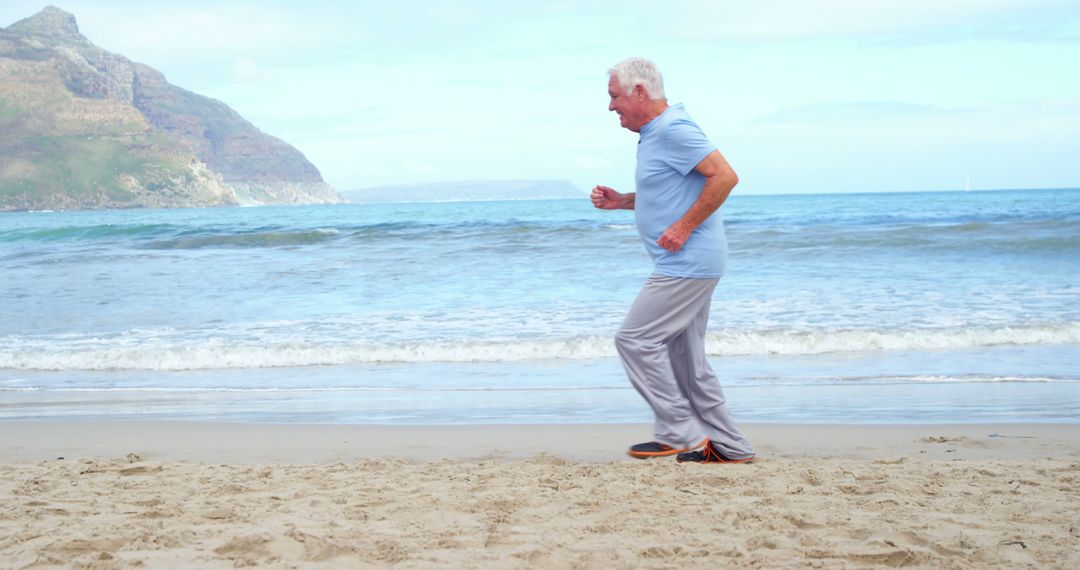 Senior Man Jogging Along Beach Shoreline on Sunny Day - Free Images, Stock Photos and Pictures on Pikwizard.com