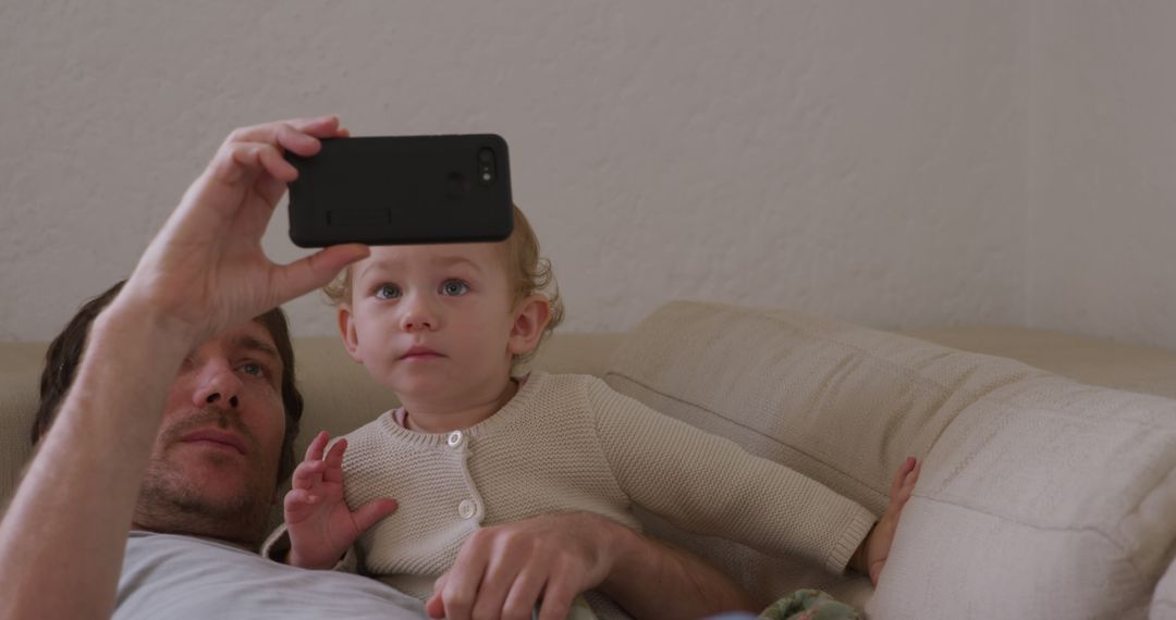 Father with toddler capturing selfie on couch - Free Images, Stock Photos and Pictures on Pikwizard.com