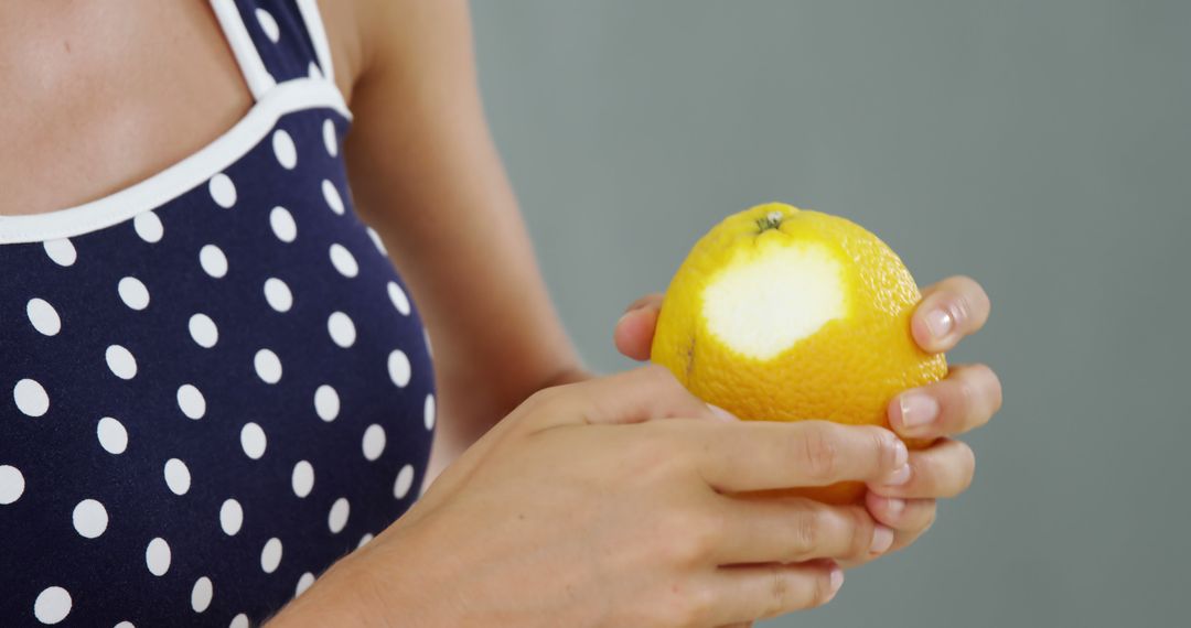 Close-up of Person Holding Partially Peeled Orange in Patterned Dress - Free Images, Stock Photos and Pictures on Pikwizard.com