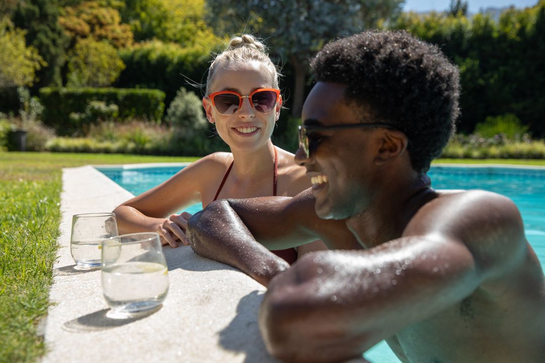 Happy Diverse Couple Relaxing by Poolside with Refreshing Drinks