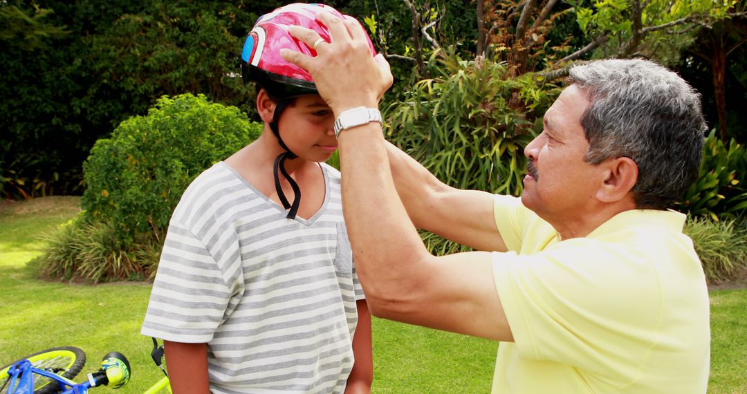 Grandfather Putting Bicycle Helmet on Grandchild in Park - Free Images, Stock Photos and Pictures on Pikwizard.com