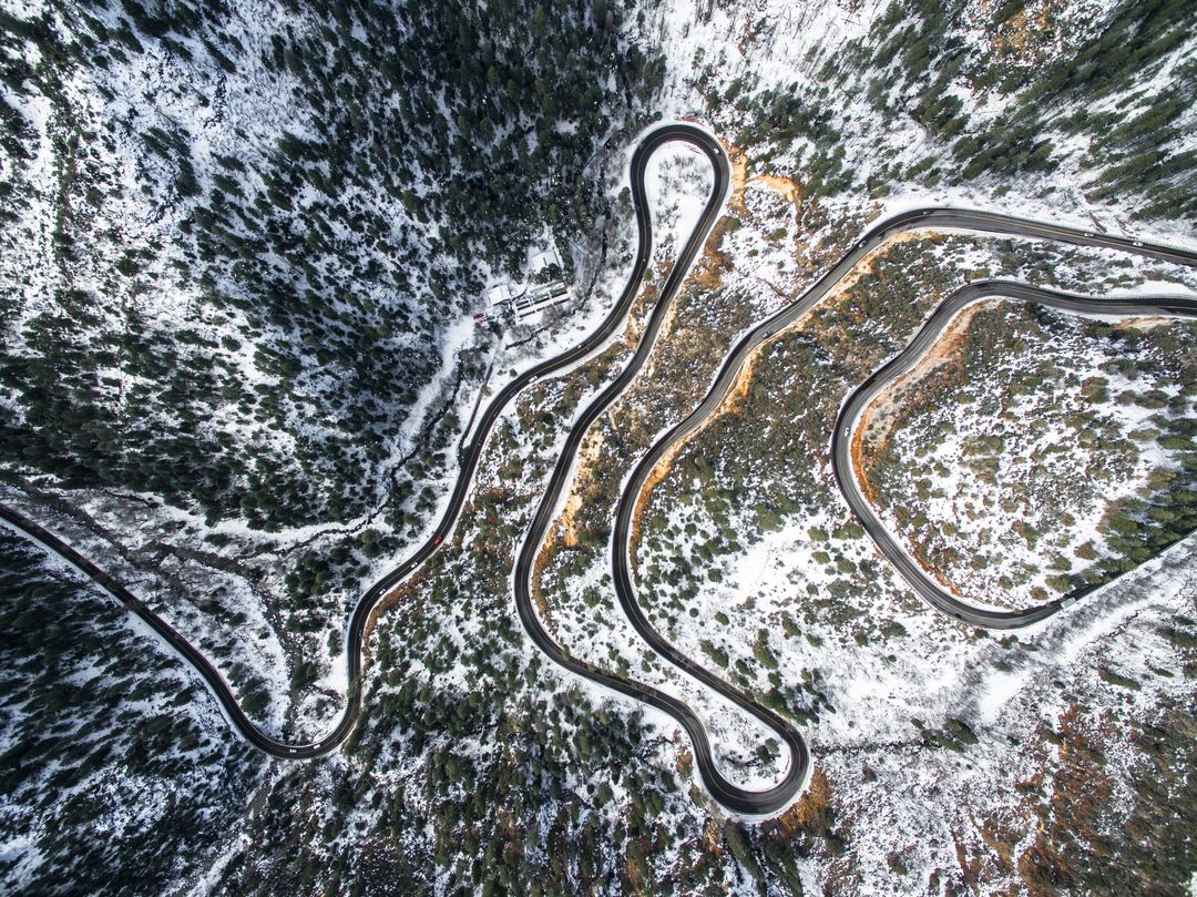 Aerial View of Winding Mountain Road Through Snowy Forest - Free Images, Stock Photos and Pictures on Pikwizard.com