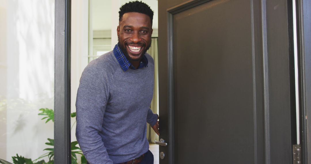 Smiling man welcomes guests into cozy home entryway