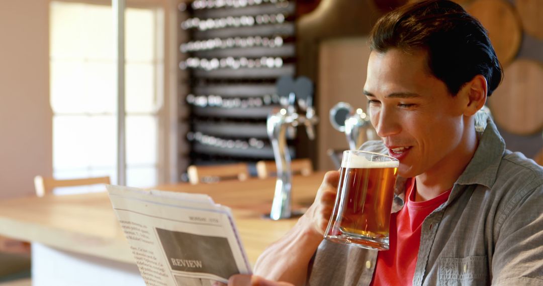 Man Reading Newspaper While Enjoying Beer in Modern Pub - Free Images, Stock Photos and Pictures on Pikwizard.com