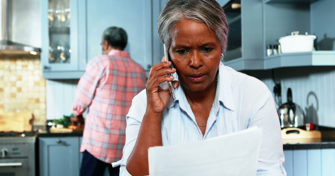 Senior Woman Discussing Paperwork on Phone in Kitchen - Free Images, Stock Photos and Pictures on Pikwizard.com