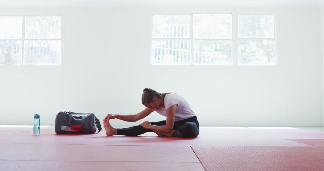 Woman Stretching on Gym Floor in Bright Room - Free Images, Stock Photos and Pictures on Pikwizard.com