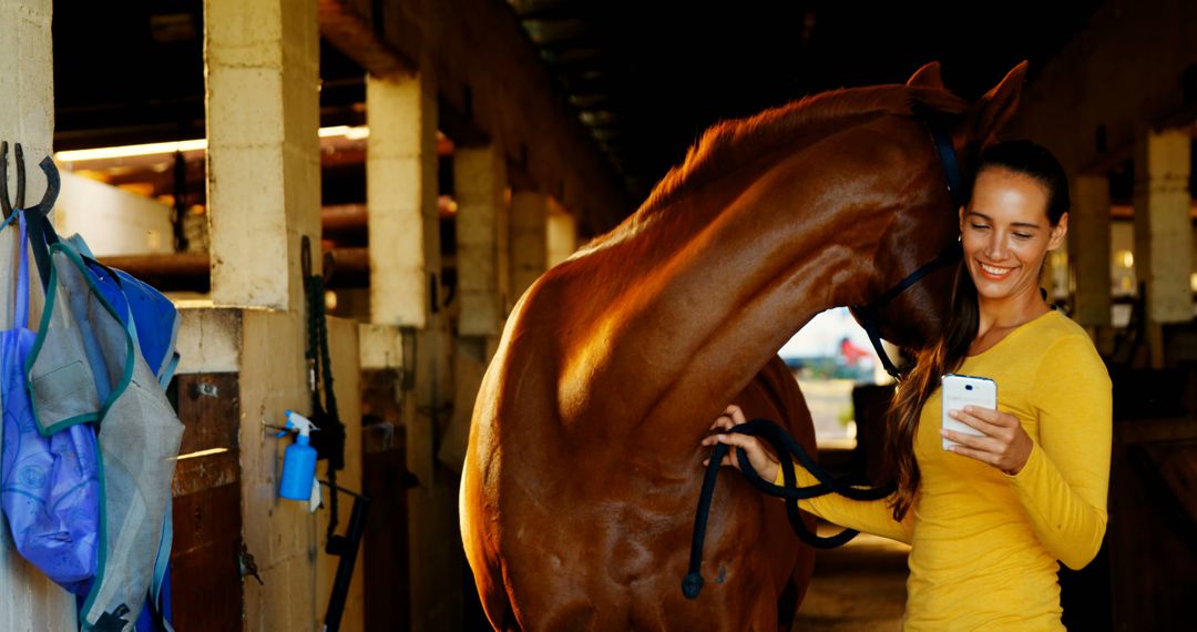 Smiling Woman with Brown Horse in Stable Using Smartphone - Free Images, Stock Photos and Pictures on Pikwizard.com