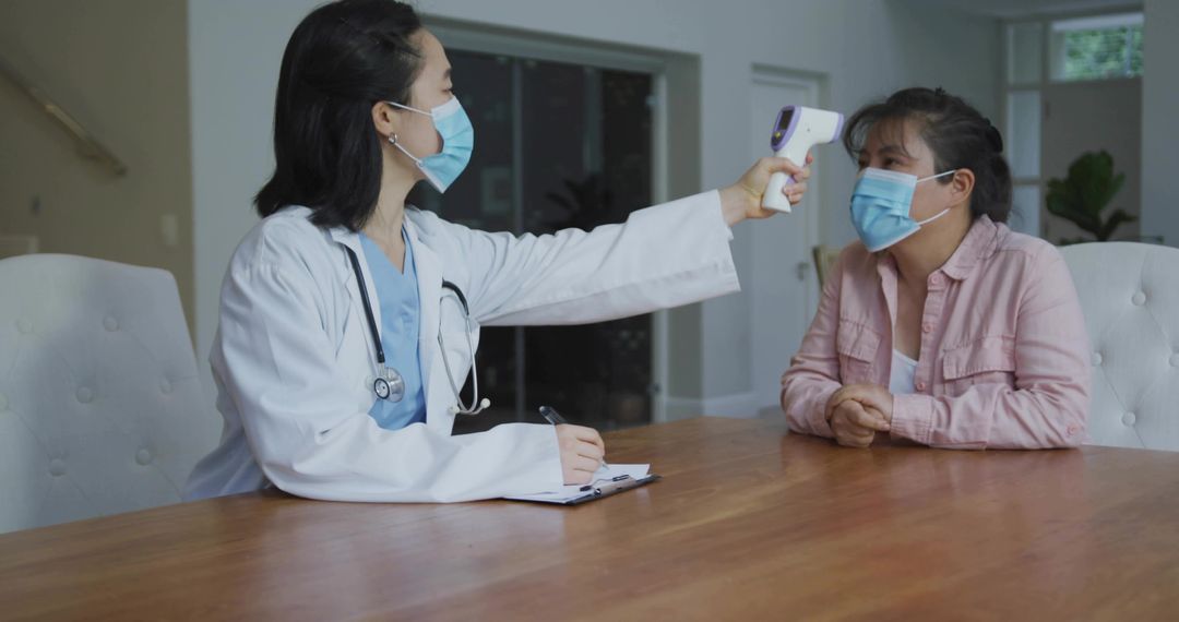 Doctor checking patient temperature with infrared thermometer during masked consultation
