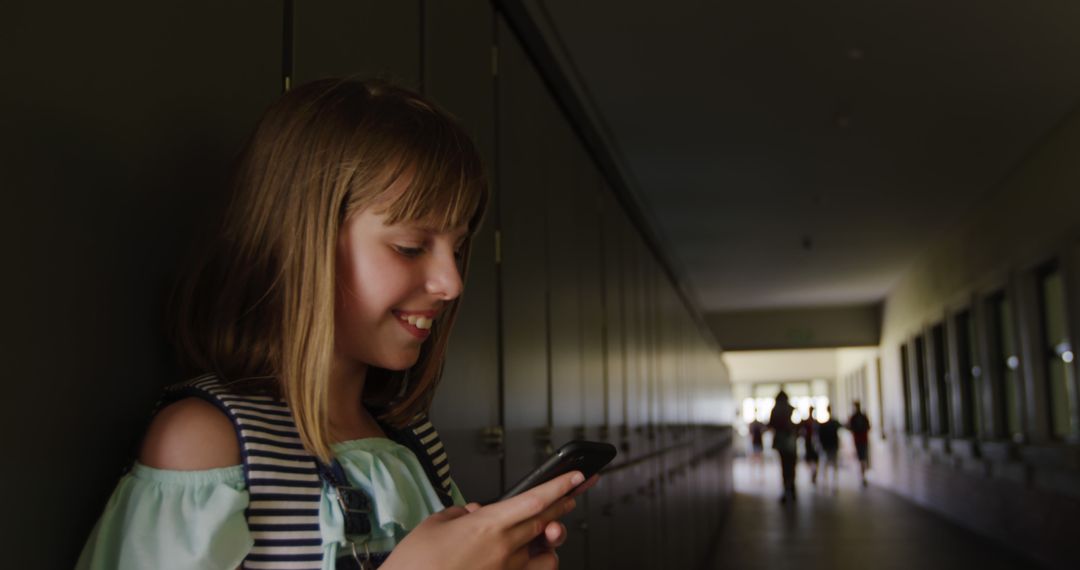 Smiling Schoolgirl Using Smartphone in Hallway Setting - Free Images, Stock Photos and Pictures on Pikwizard.com