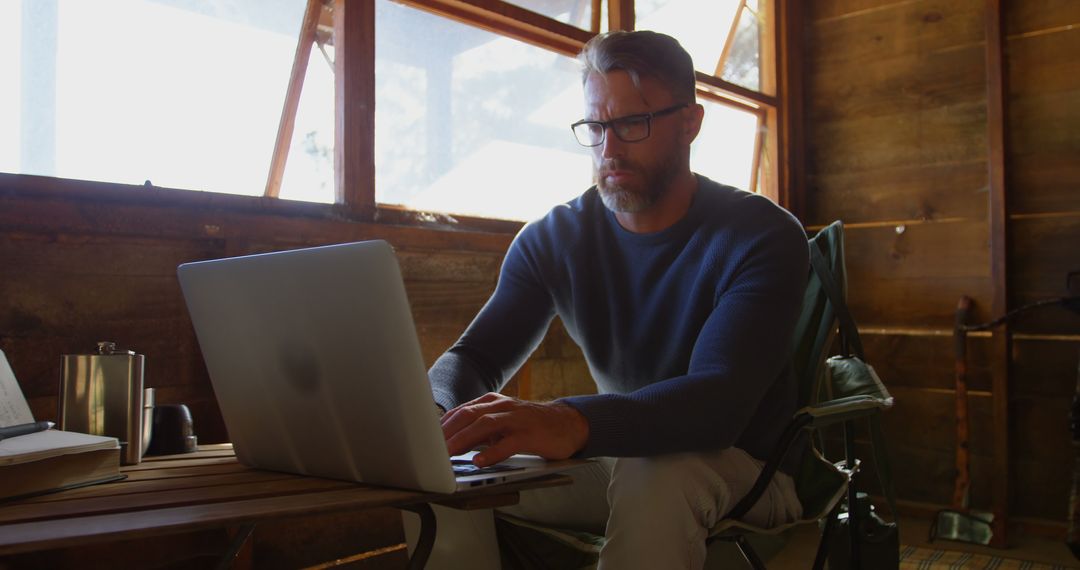 Man Working Remotely in Rustic Cabin with Laptop - Free Images, Stock Photos and Pictures on Pikwizard.com