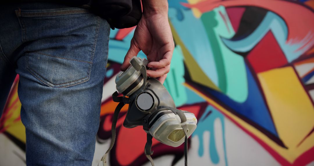 Street Artist Holding Respirator Near Vibrant Graffiti Mural - Free Images, Stock Photos and Pictures on Pikwizard.com