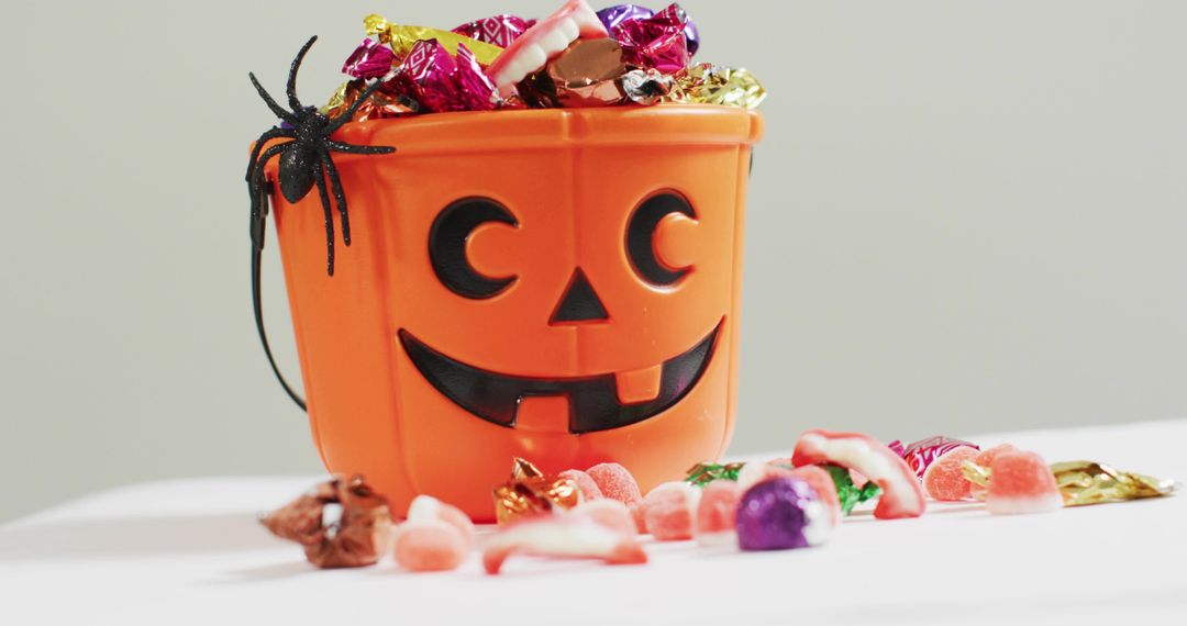 Orange Jack-o-Lantern Candy Bucket Overflowing with Wrapped Sweets and Gummy Teeth