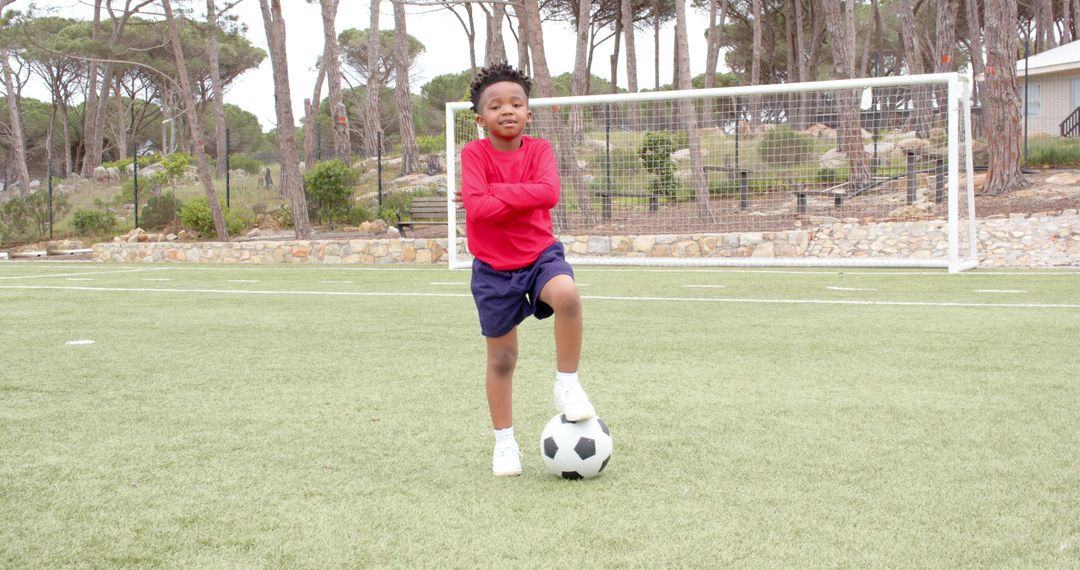 Confident Boy Practicing Soccer on Grass Field