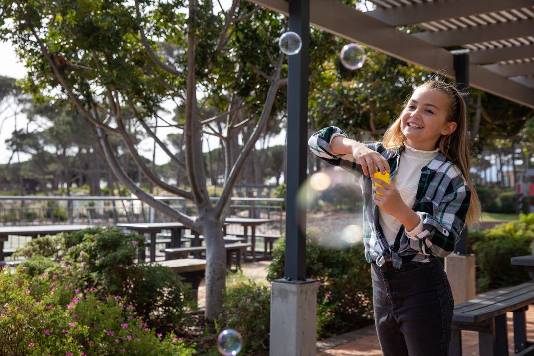 Happy Girl Creating Soap Bubbles in Park on Sunny Day