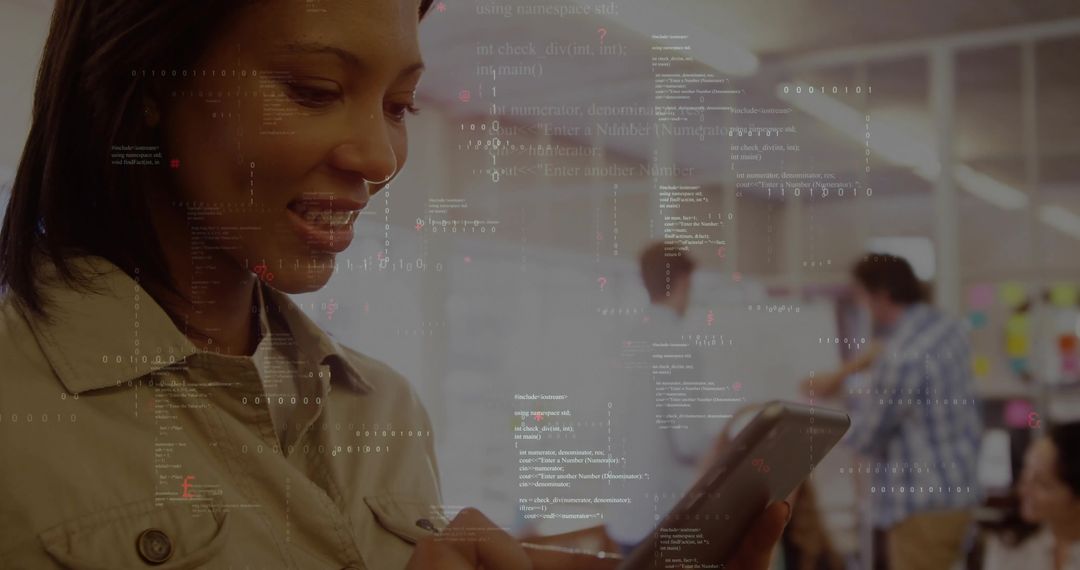 Smiling woman tapping tablet with floating code overlay in open-plan coworking office