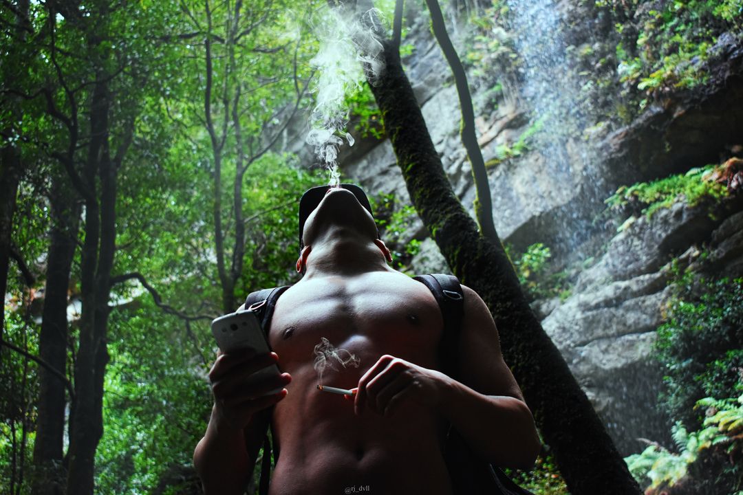 Man smoking cigarette in lush forest, enjoying nature's serenity - Free Images, Stock Photos and Pictures on Pikwizard.com
