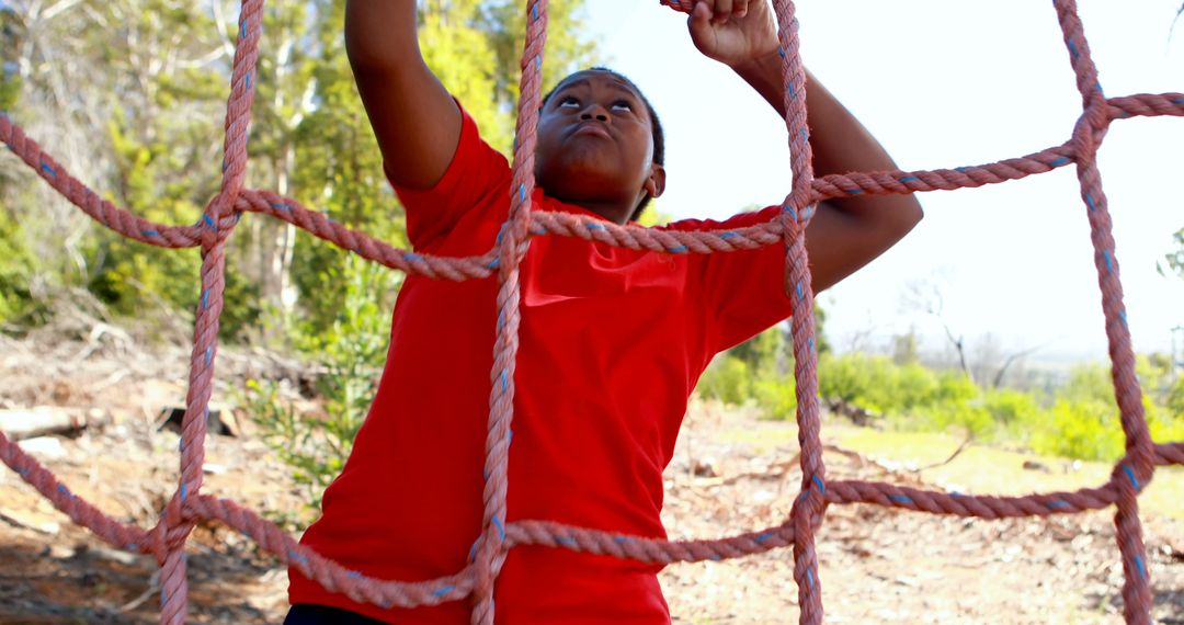 African American Boy Climbing Outdoor Rope Net with Determination - Free Images, Stock Photos and Pictures on Pikwizard.com