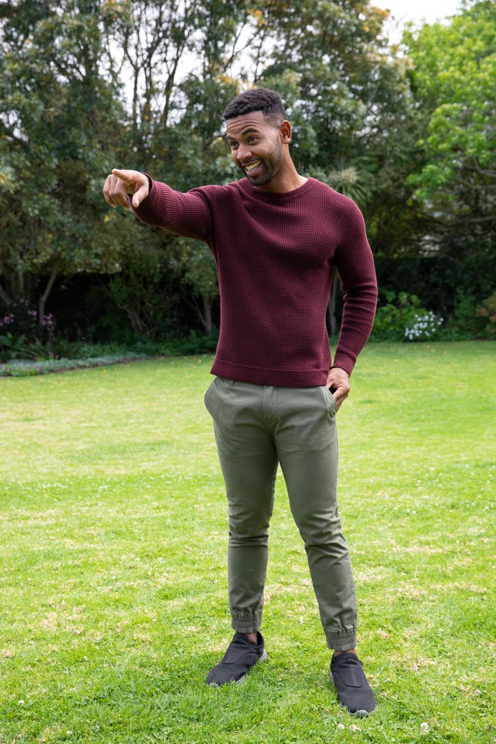Smiling Man Gesturing on Lawn in Casual Attire