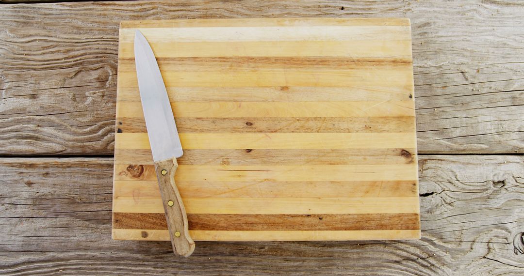A kitchen knife rests on a well-used wooden cutting board, with copy space - Free Images, Stock Photos and Pictures on Pikwizard.com