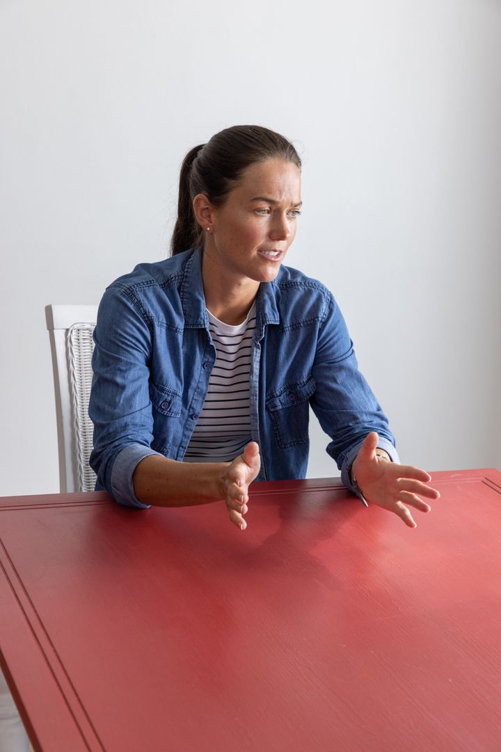 Woman Expressing With Hands at Modern Red Table in Minimalistic Room