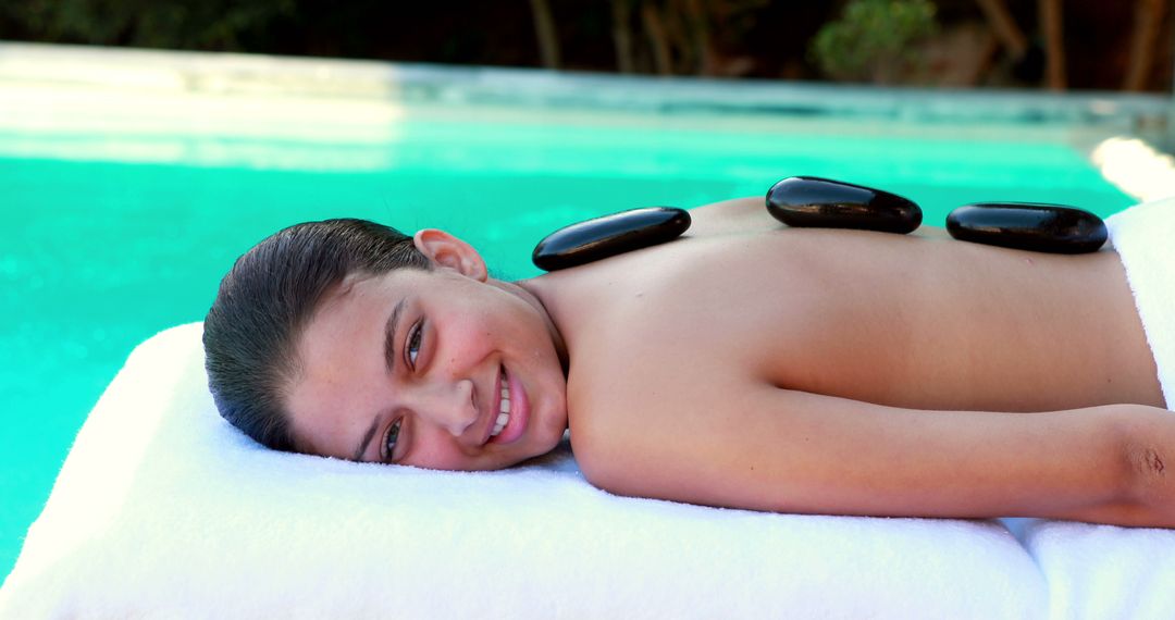 Young Woman Enjoying Hot Stone Massage by Poolside - Free Images, Stock Photos and Pictures on Pikwizard.com